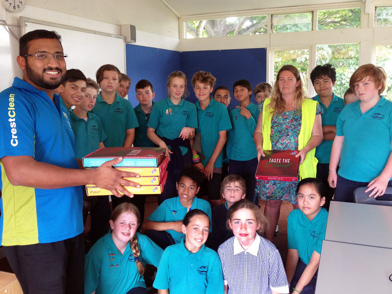 Titus Samuel hands out pizza to Room 7 pupils at Bamford School in Christchurch.