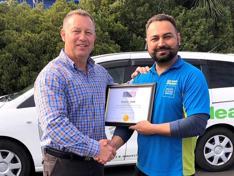 Robert Glenie presents Randeep Singh with a certificate from Master Cleaners Training Institute for an upskilling course in carpet care. 