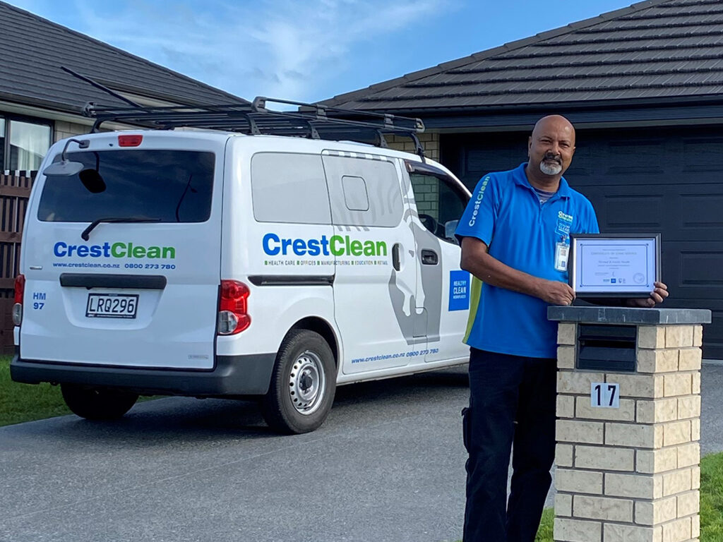 Cleaner standing outside his home with a long service certificate.