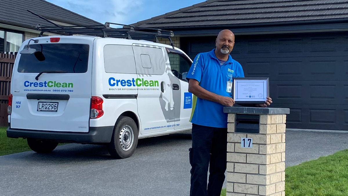 Cleaner standing outside his home with a long service certificate.