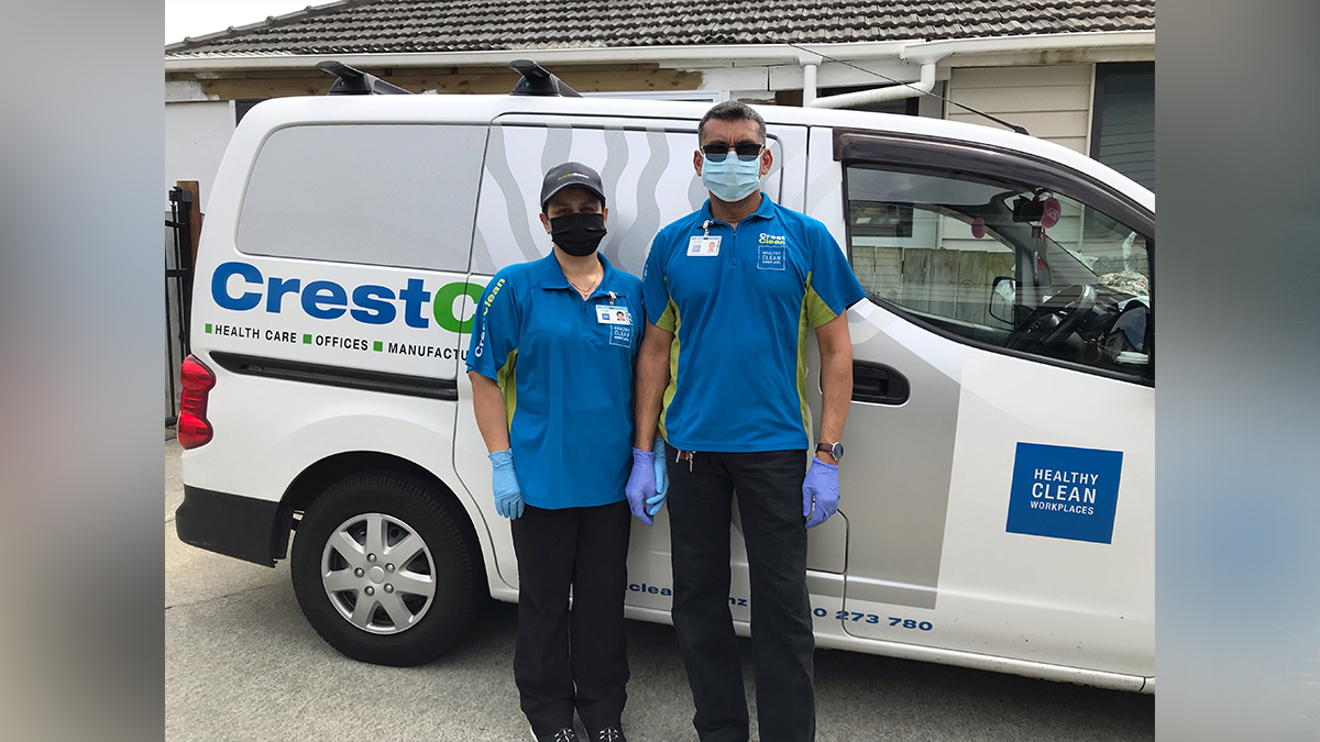 Cleaners wearing masks, standing by their van.